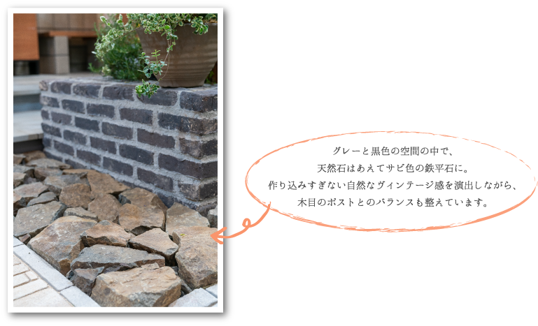 グレーと黒色の空間の中で、 天然石はあえてサビ色の鉄平石に。 作り込みすぎない自然なヴィンテージ感を演出しながら、 木目のポストとのバランスも整えています。